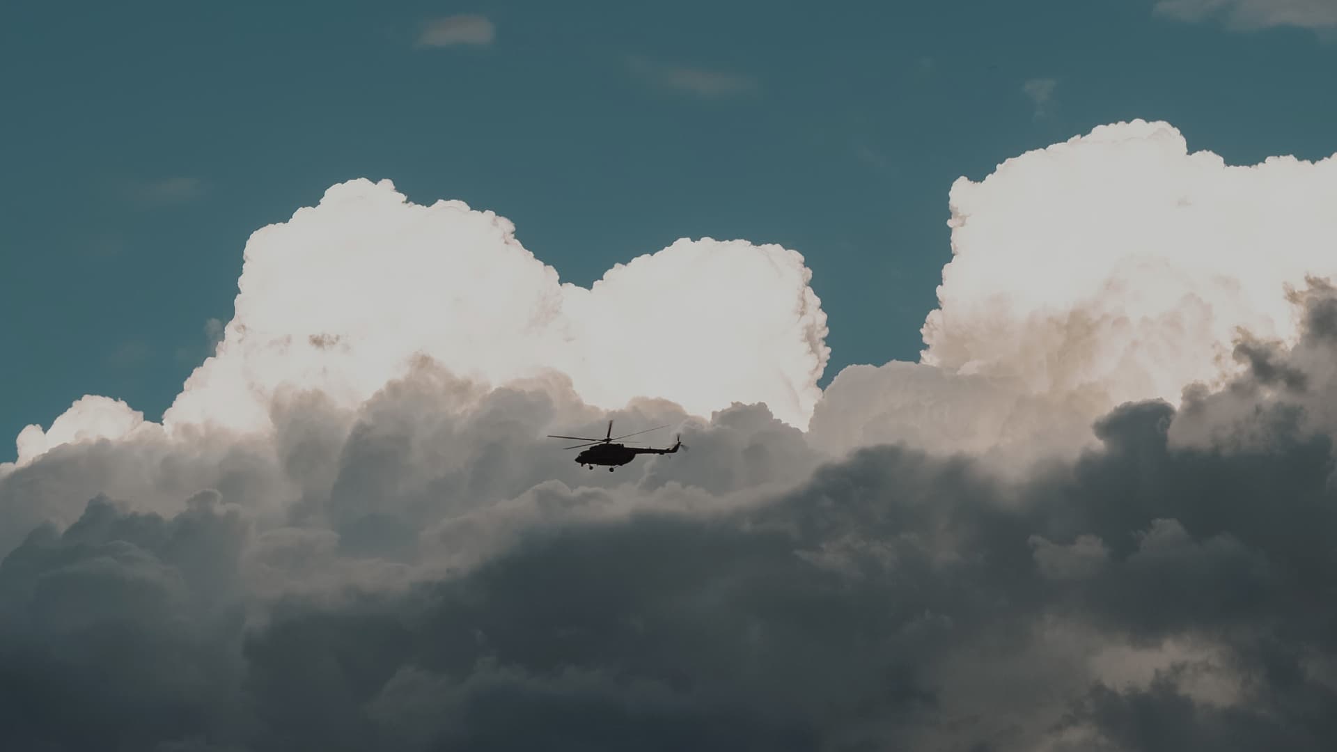 Helicopter flying near massive clouds